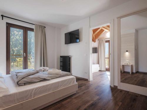 蓬泰迪莱尼奥Hotel Garnì Alta Valle的白色的卧室设有床和大窗户