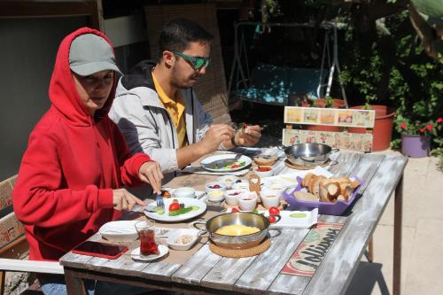 达特恰Eski Datça Pansiyon的坐在餐桌旁吃饭的男人和女人