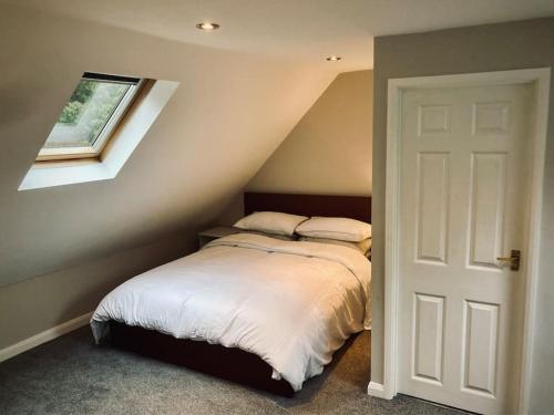法纳姆Owl Tree Cottage with access to Alice Holt的一间卧室配有一张带白色床单的床和一扇窗户。