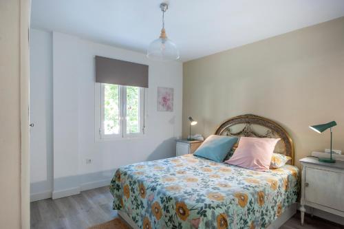 塞维利亚Casa Valentina: Confort y Luz en Sevilla Centro的一间卧室配有一张带花卉床罩的床和窗户。