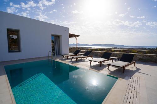 普恩达Kouros Blanc Resort & Suites的一个带躺椅的游泳池以及一座房子