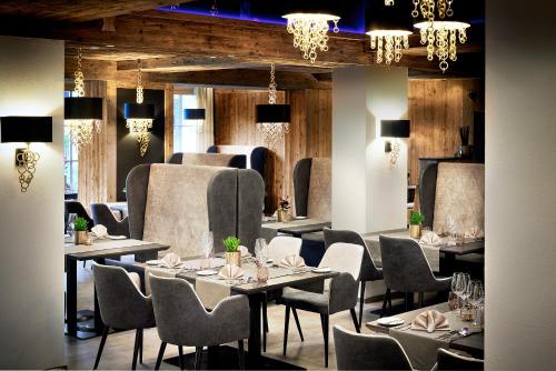 埃尔毛伊尔玛因提洛尔运动酒店的用餐室配有桌椅和吊灯。