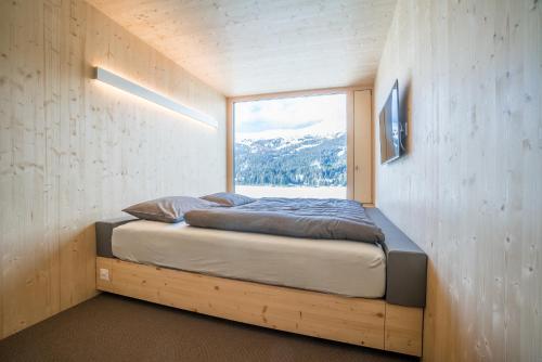 伦策海德Revier Mountain Lodge Lenzerheide的一张位于带大窗户的房间内的床铺