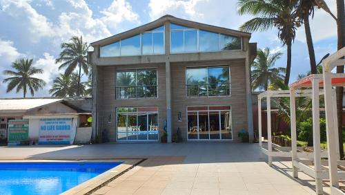 Elwa热带海滩度假村的一座带游泳池和棕榈树的大房子