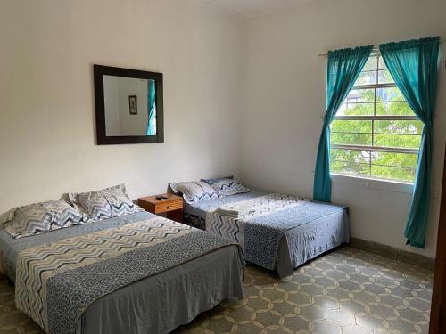圣萨尔瓦多Hostal Cumbres del Volcan Flor Blanca的配有镜子和窗户的客房内的两张床