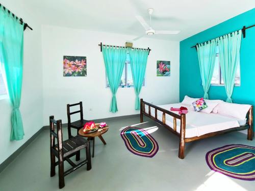 南威Frangipani House Nungwi Zanzibar的一间卧室配有两张床和一张桌子及椅子