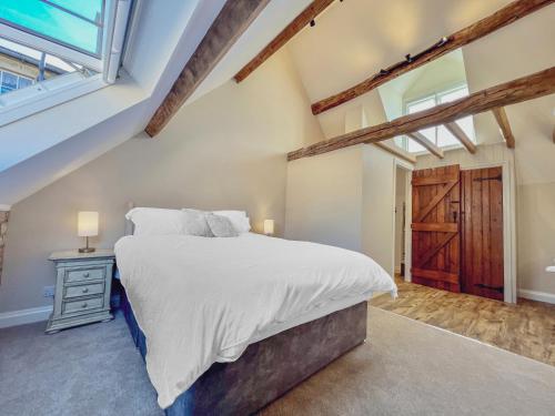 奇平卡姆登Grooms Lodge, Chipping Campden - Taswell Retreats的一间卧室设有一张大床和一个窗户。