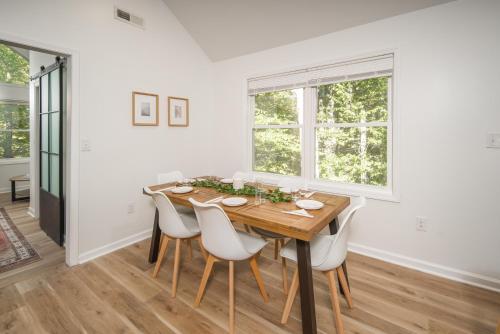 布恩The Wanderer Guesthouse的一间带木桌和白色椅子的用餐室