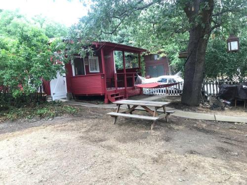 朱利安Cozy, Cheerful & Charming Cabin - Historic Julian的红色小屋前的野餐桌,有树