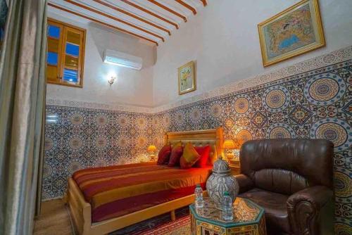 非斯Dar lmrama Guest House Fes Medina Morocco的一间卧室配有一张床、一把椅子和一张桌子