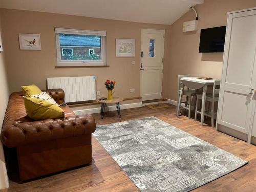 Wisborough GreenTulip Cottage的客厅配有真皮沙发和桌子