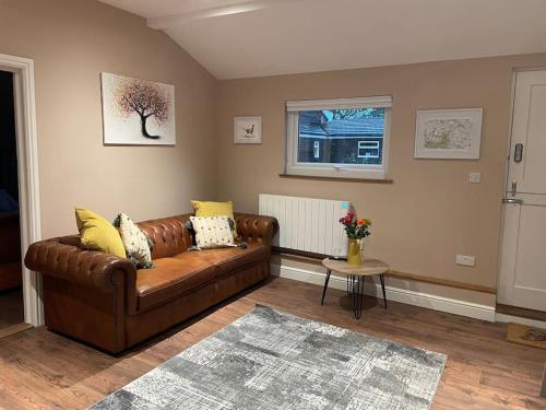 Wisborough GreenTulip Cottage的客厅配有棕色皮革沙发和窗户