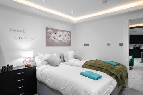 纽伯里Aryas Apartments Newbury的一间白色卧室,配有两张床和梳妆台