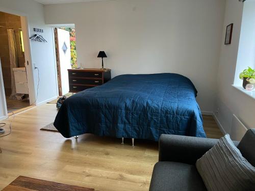 巴勒鲁普Jonstrupvejens Apartments Lejl B的一间卧室配有一张带蓝色床罩和沙发的床。