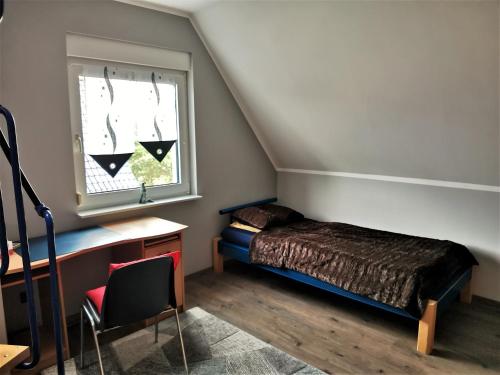 PotzlowFerienhaus Frank的一间卧室配有一张床、一张书桌和一个窗户。