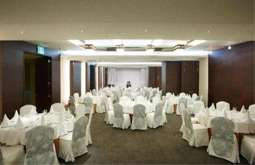 首尔Niagara Hotel的宴会厅配有白色的桌椅和男人