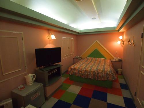 佐野市ホテルシンフォニー佐野店大人専用的一间卧室配有一张床和一台电视。
