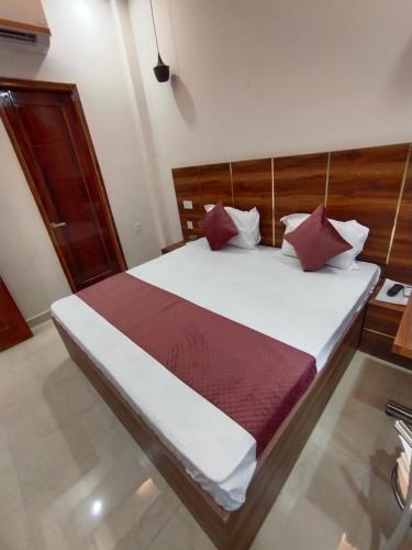 齐拉克普尔Hotel kartik的卧室配有带红色枕头的大型白色床