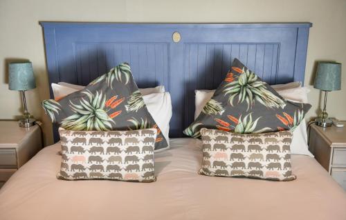 弗朗斯胡克Cabriere Cottage的床上的2个枕头和蓝色床头板