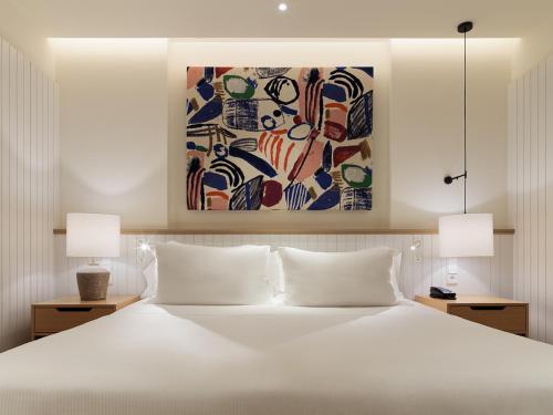 马拉加H10 Croma Málaga的一间卧室配有一张带两盏灯的大型白色床。