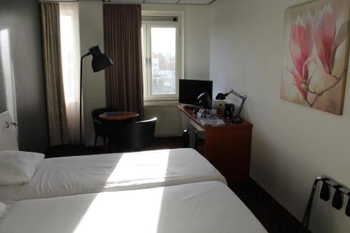 海牙海牙弗莱彻酒店的酒店客房设有两张床和一张带电脑的书桌