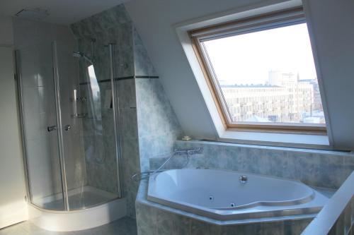 海牙海牙弗莱彻酒店的一间带浴缸和淋浴的浴室以及窗户。