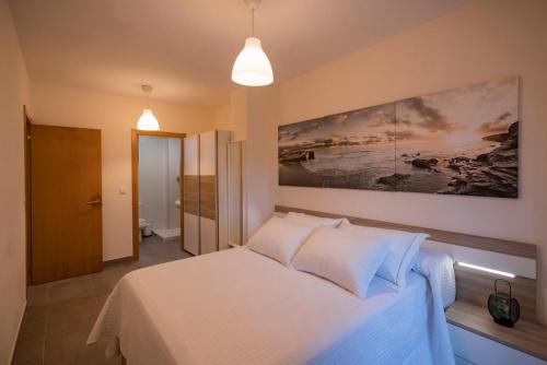 JoveArea Suites的卧室配有白色的床和墙上的绘画作品