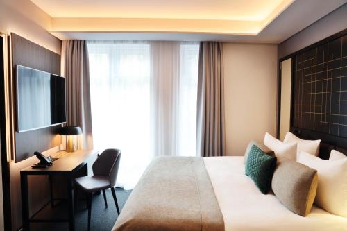 雷克雅未克Hótel Reykjavík Saga的酒店客房配有一张床、一张书桌和一台电视。