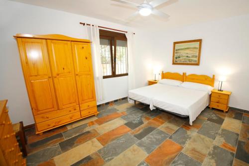 OnilSenia Tomaset III的一间卧室配有一张床和一个木制橱柜