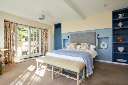 FrilshamThe Royal Oak, Yattendon的一间卧室设有蓝色的墙壁和一张带长凳的床