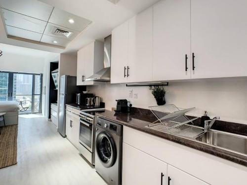 迪拜Luxury Modern Studio in JLT with Amazing View & Rooftop Pool - sleeps 3的厨房配有白色橱柜、水槽和洗碗机。