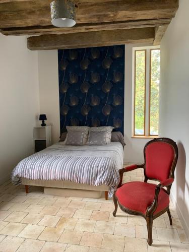 吕讷La Grange d Ave的一间卧室配有一张床和一张红色椅子