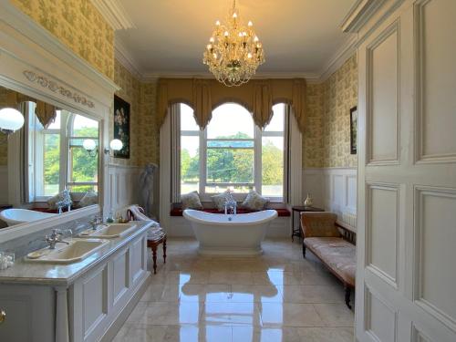 唐克斯特Rossington Hall的带浴缸、两个盥洗盆和吊灯的浴室。