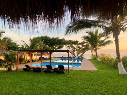 翡翠海岸Mar De Estrellas - Hotel的一个带椅子和棕榈树的游泳池的度假酒店