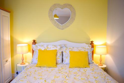 PakefieldAvocet - Suffolk Coastal Escapes的一间卧室配有一张带黄色枕头和镜子的床