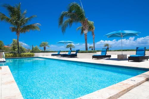 Turtle CoveLa Vista Azul - Lovely Spacious Condo close to Grace Bay - Free Wi-Fi的一个带蓝色椅子的游泳池,棕榈树