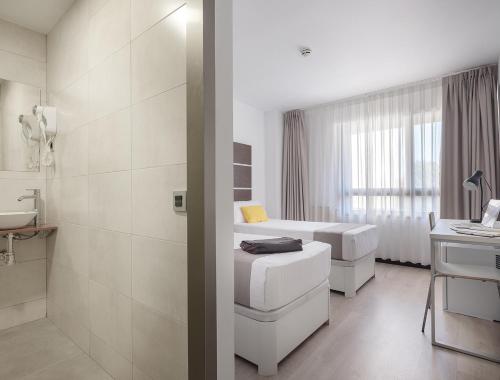 马德里Roisa Hostal Boutique的白色的浴室设有两张床和盥洗盆