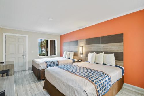 可可比奇安东尼海滩汽车旅馆的酒店客房设有两张床和橙色的墙壁。