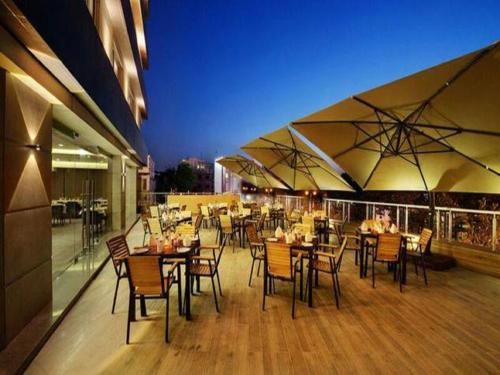 巴罗达Hotel Suba Elite Vadodara的一间带桌椅和遮阳伞的餐厅