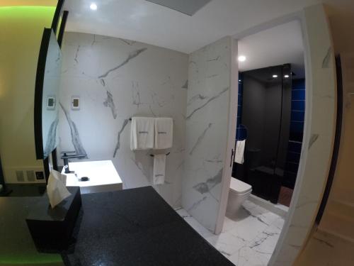 墨西哥城WeEnjoy Hotels Grand Prix Aeropuerto CDMX的一间铺有白色大理石墙的浴室