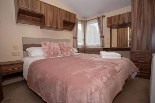 南塞尔尼Willow View - Hoburne Cotswolds Holiday Park的一间卧室配有一张带粉色毯子的大床