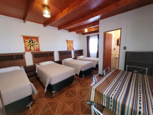 圣佩德罗·德·阿塔卡马Lalck Cketi Hospedaje y Turismo的酒店客房设有三张床和壁炉