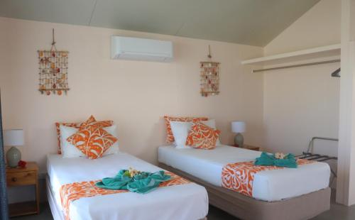 阿鲁坦加蓝姬尼斯度假酒店的一间卧室配有两张带橙色和白色床单的床