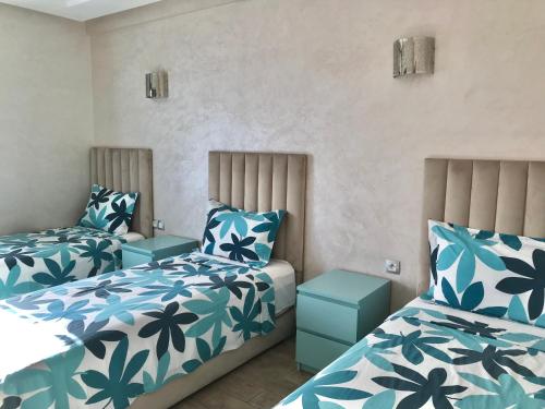 曼苏里亚Marbella Beach location pour famille 2 chambres的一间卧室配有两张带蓝白色床单的床