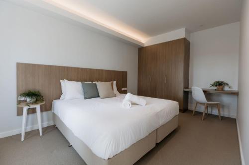 卡拉拉海滩Beach & Bay Stay Motel的卧室配有一张白色大床和一张书桌