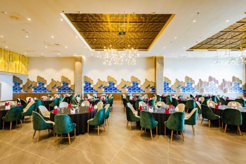 下龙湾Muong Thanh Luxury Ha Long Centre II的一个带桌椅的宴会厅和一个大墙