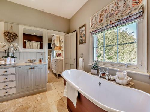汉默Willington Lodge的带浴缸和窗户的大浴室