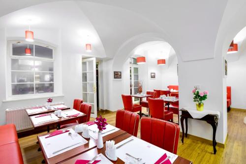 布拉格Hotel Residence Green Lobster的餐厅设有木桌和红色椅子