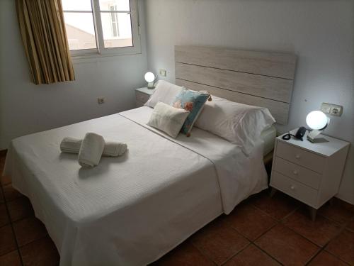 圣何塞维斯塔玛尔圣何塞公寓式酒店的卧室配有白色的床和2条毛巾