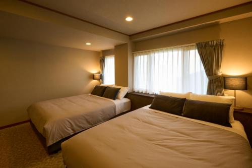Nakanoスイートヴィラ オーシャンビュー南熱海的酒店客房设有两张床和窗户。